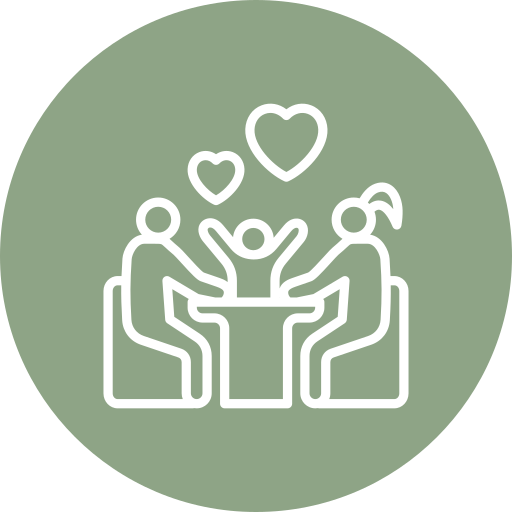 White outline of two adults and a child sitting at a table, with hearts above them, on a green circular background, representing family love or bonding.